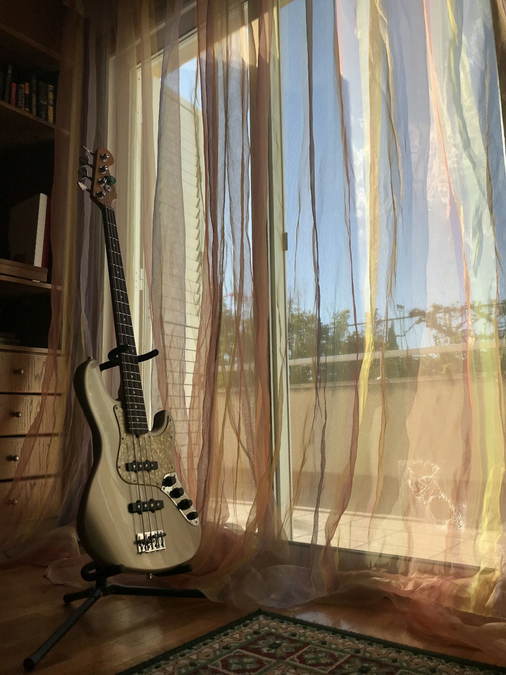 gray electric bass guitar beside window