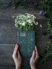 woman holds Familiar Wild and Flowers book on common daisies on brown panel