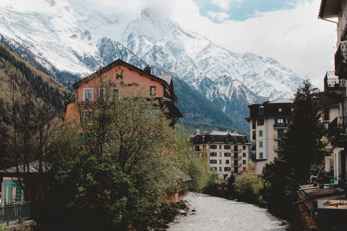 A river running between buildings in Chamonix, under a snowy mountain