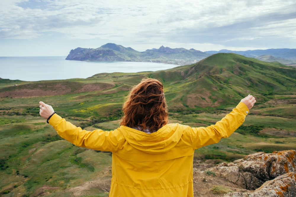 woman standing on hill in front of body of water