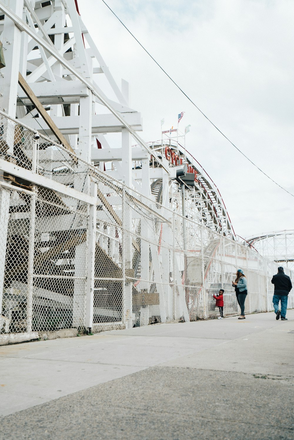 three person standing near white fence