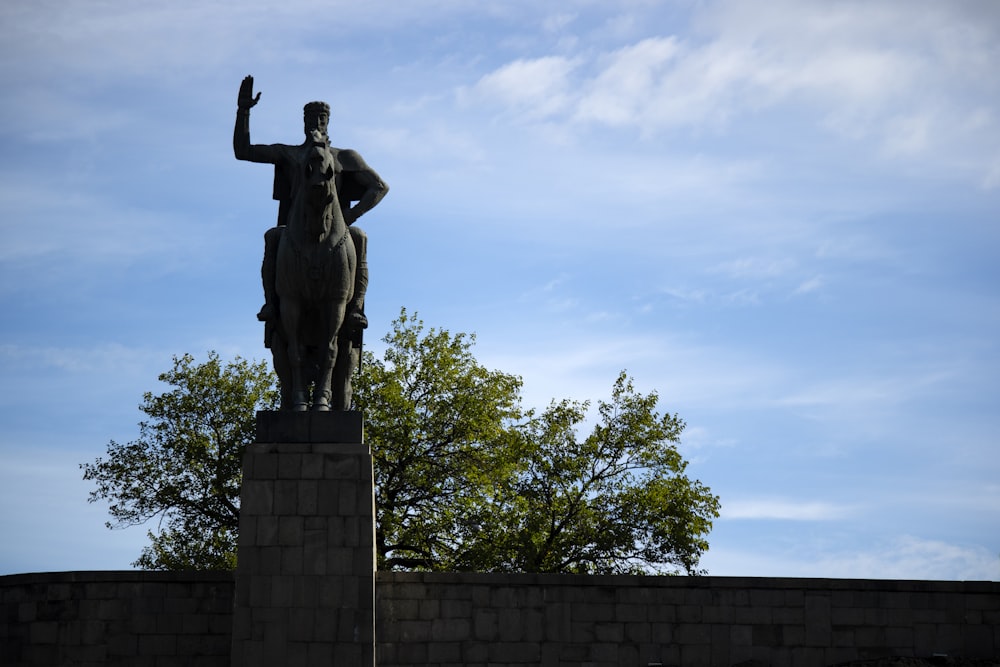 man riding horse statue near tree