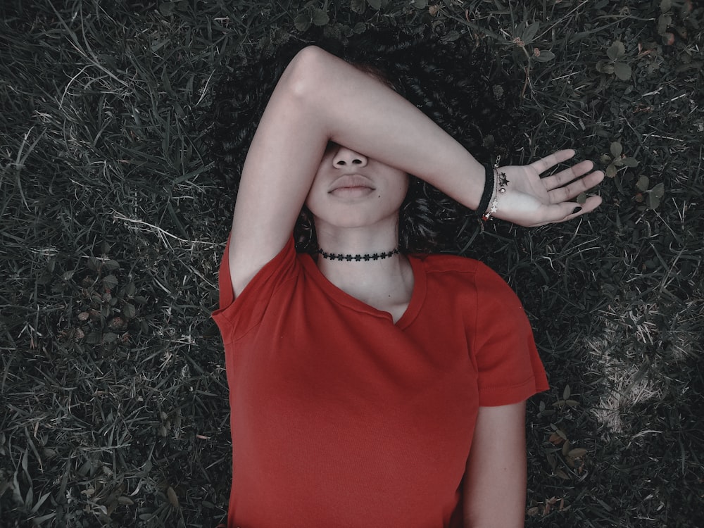 woman in red crew neck t-shirt lying on grey ground