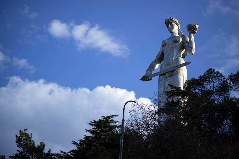 woman holding sword statue near trees