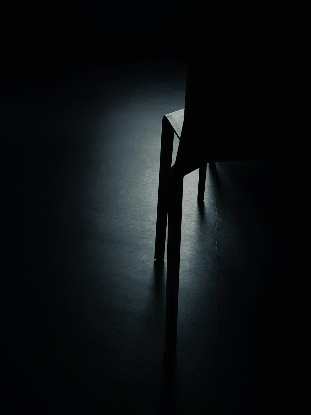 uma foto em preto e branco de uma cadeira no escuro