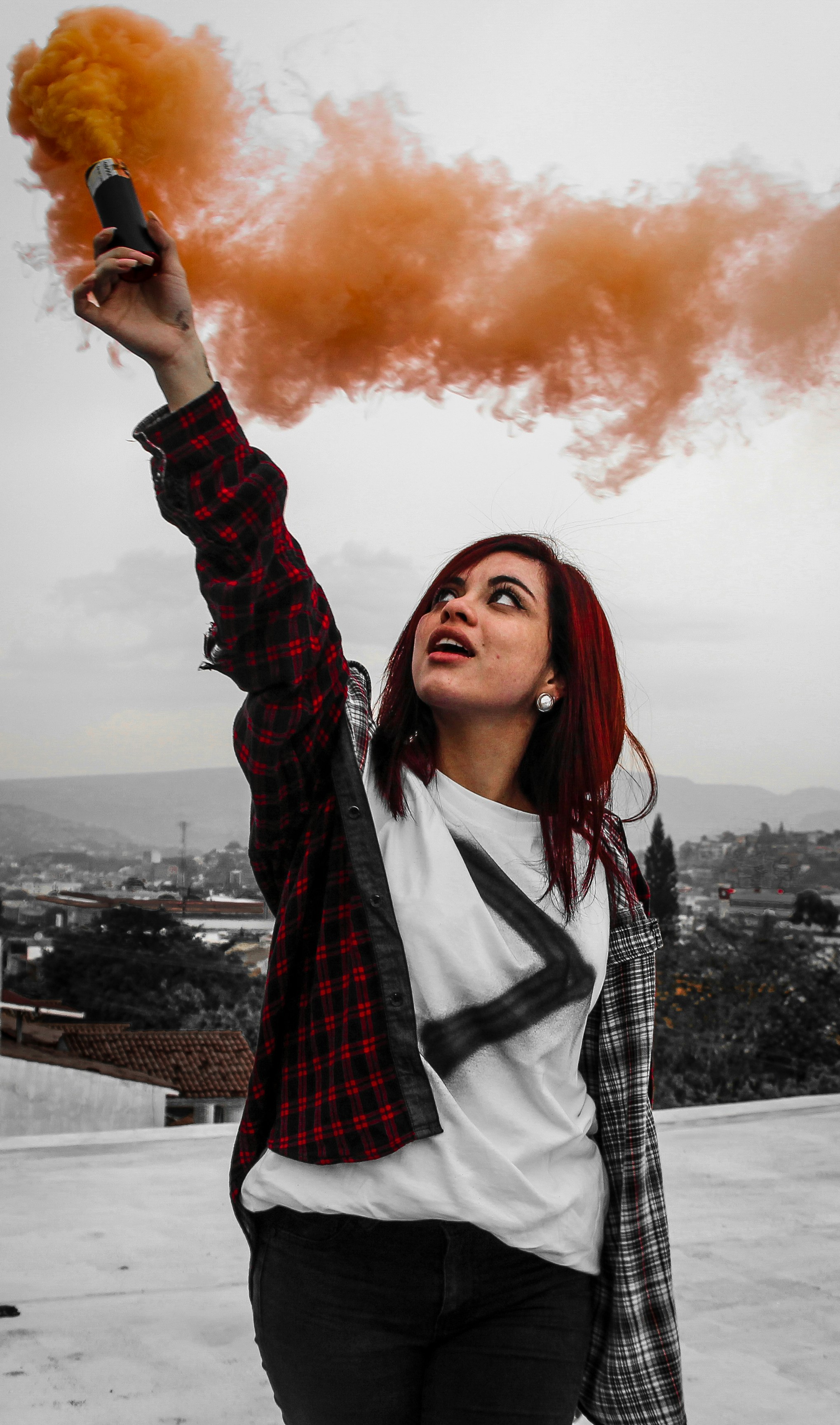 mujer sosteniendo bengalas de humo naranja en la azotea