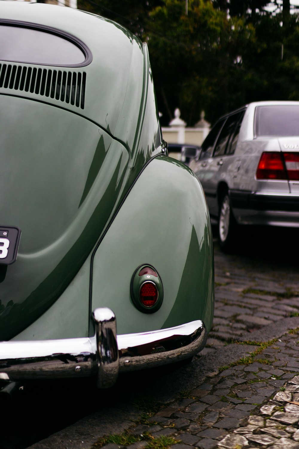 Volkswagen Maggiolino verde parcheggiato vicino a un veicolo grigio