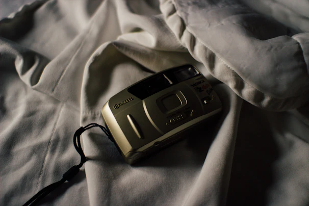 A moody, elegant shot of a vintage film camera casting shadows on a dark textured surface.