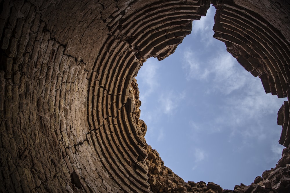 a hole in a brick wall with a sky in the background