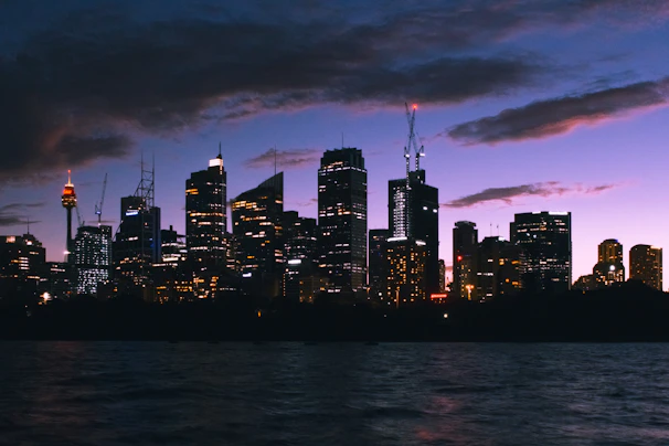A dramatic aerial shot of Leicester city skyline at twilight with glowing lights and deep blue skies.