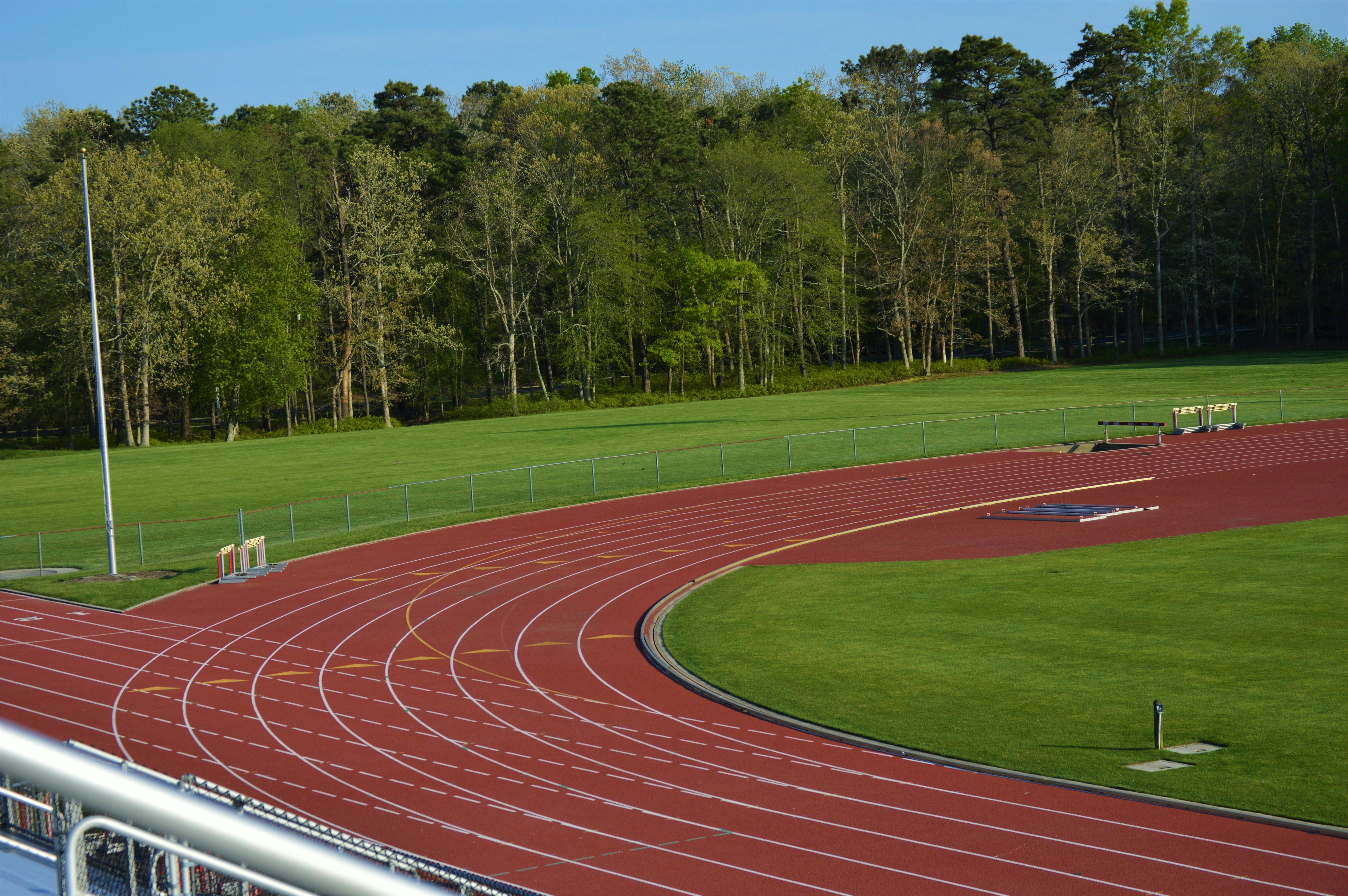 Green school sports ground with running track in bright sunny day