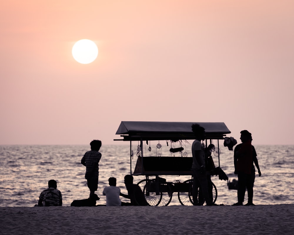 silhouette di persone in riva al mare durante l'alba