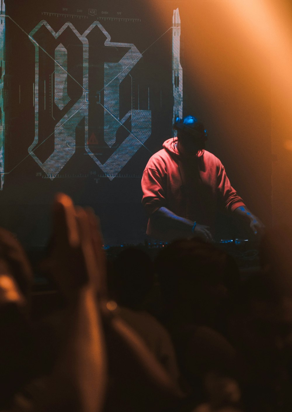 Mann in rotem Kapuzenpullover mit Kopfhörern bedient DJ-Mixer-Maschine