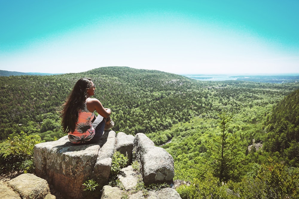 woman in orange and black sleeveless top on rock