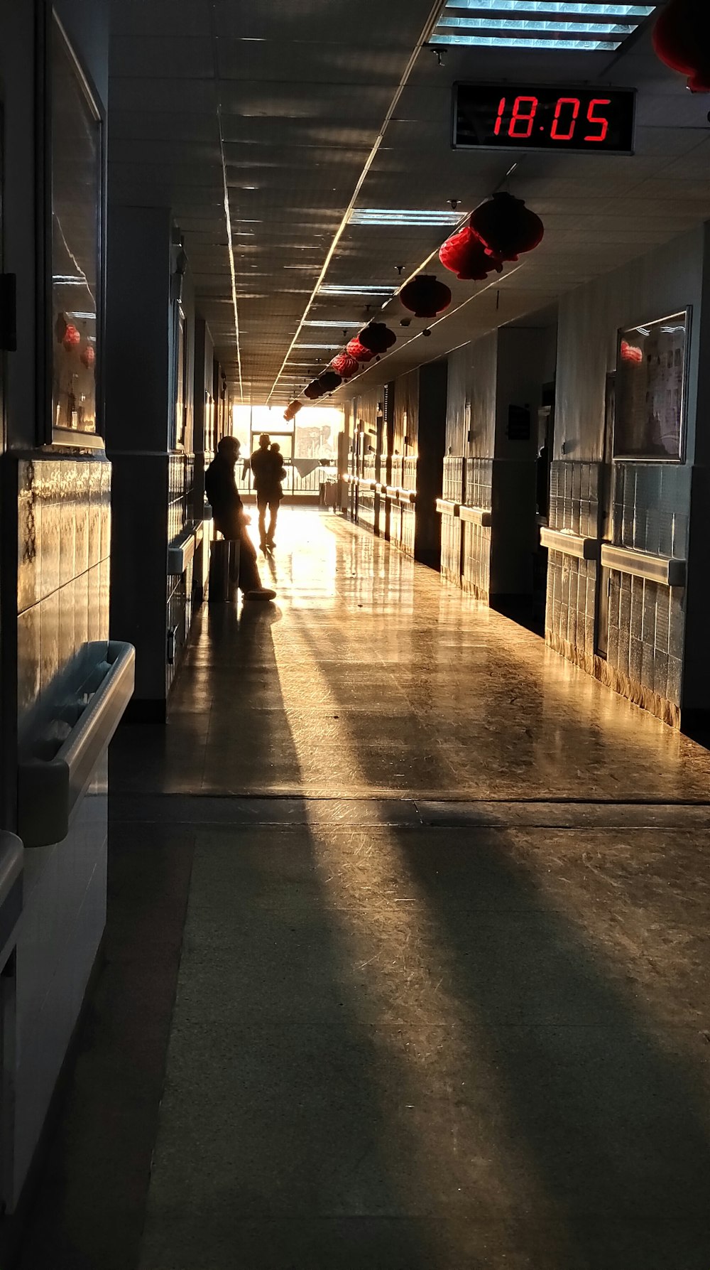 person leaning against the wall inside building showing 18:05 time