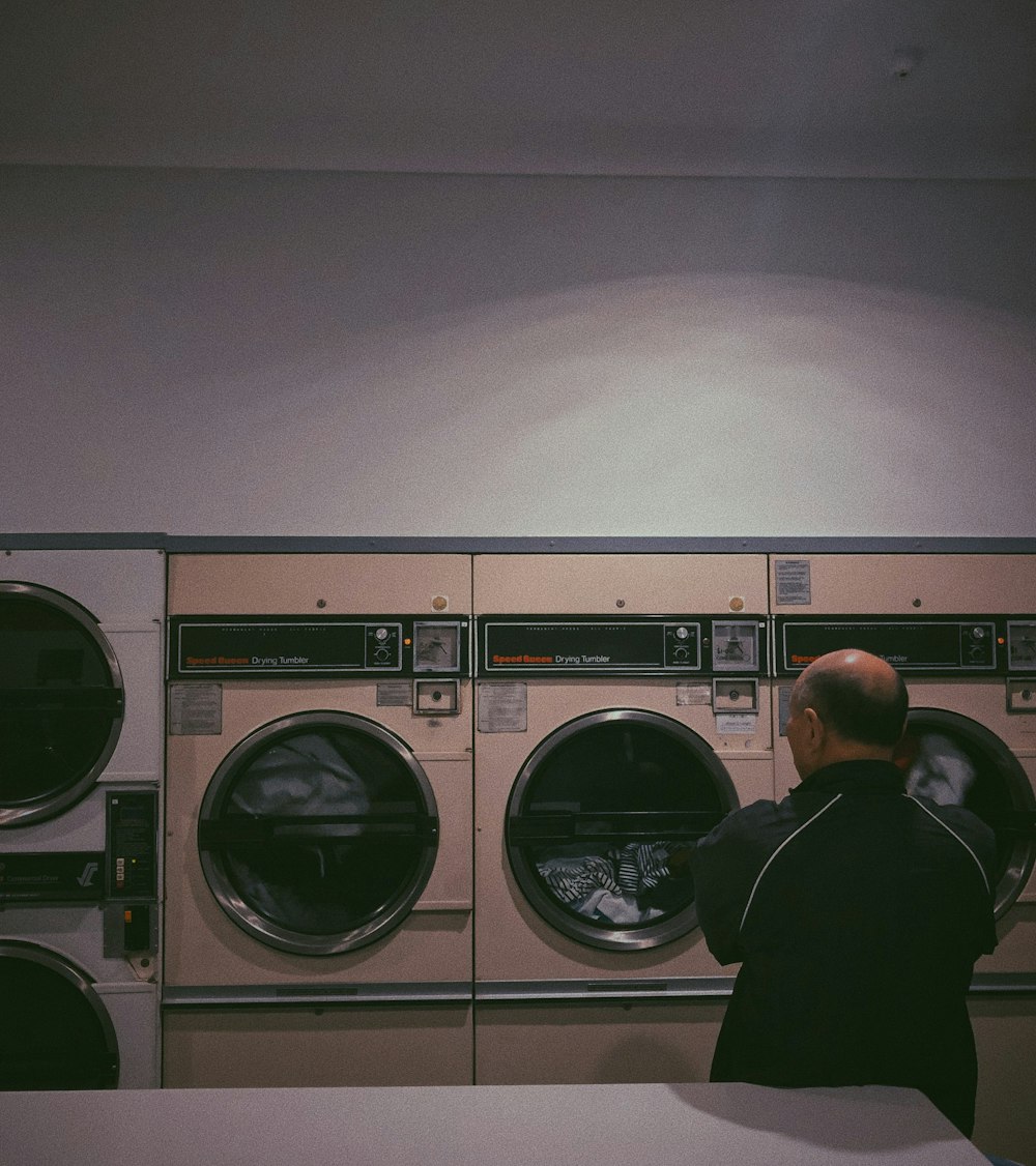 man standing and facing clothes inside front-load laundry machine