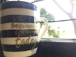 A stylish mug featuring an inspirational quote next to a steaming cup of coffee.