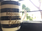 A stylish mug featuring an inspirational quote next to a steaming cup of coffee.