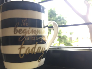 A cozy mug adorned with a motivational quote and warm sunset gradient, resting on a wooden table.