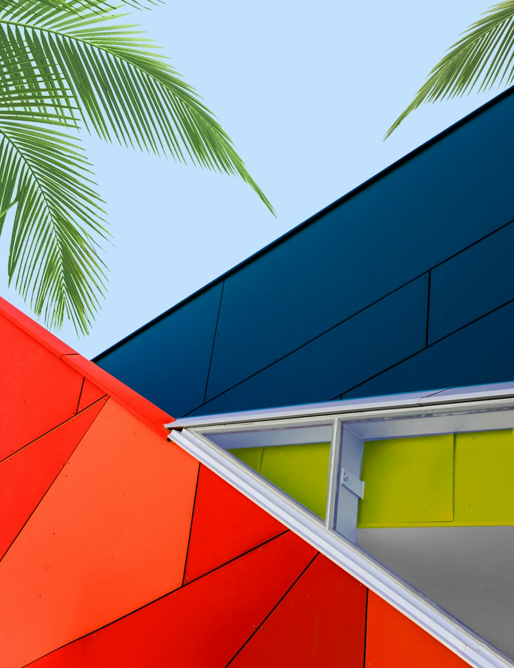 red, blue, and green glass building near palm trees