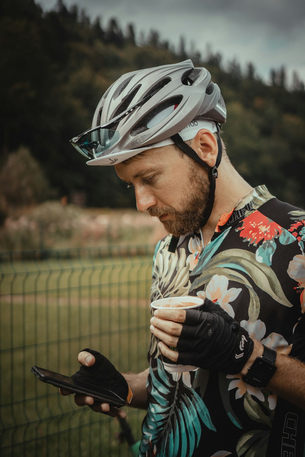 man wearing black and multicolored floral shirt holding smartphone