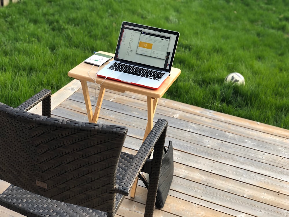 black wicker chair near brown foldable table with MacBook Pro turned-on
