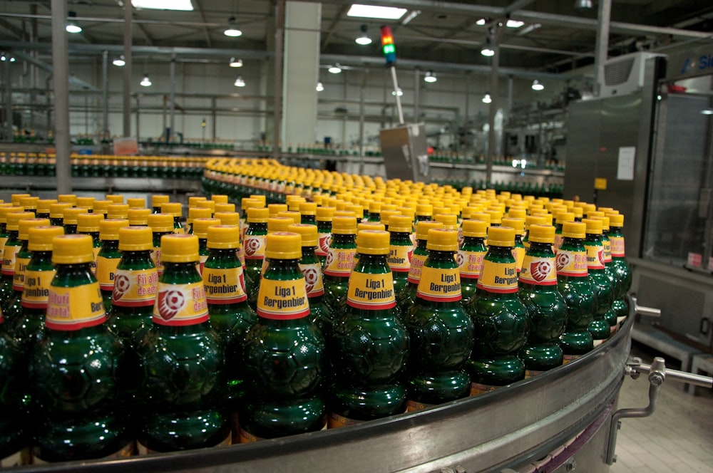 Lote de botellas amarillas y verdes en máquina industrial