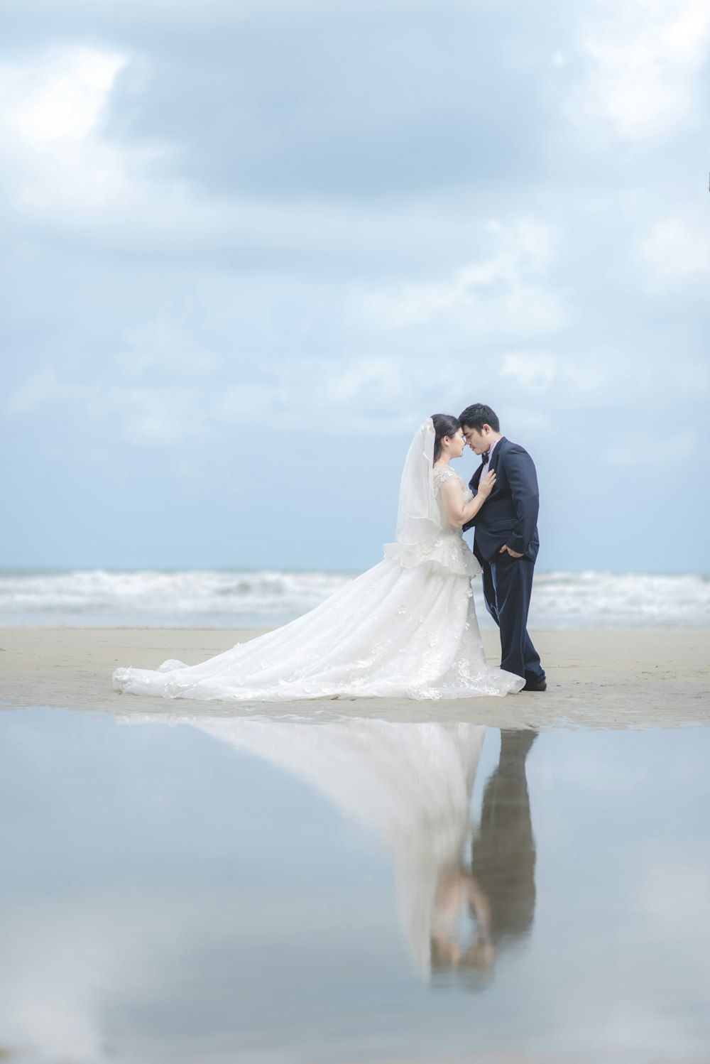 groom and bride reflection on body of water during daytime