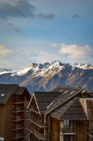 A panoramic view of a snowy Swiss chalet nestled in the Alps during golden hour.