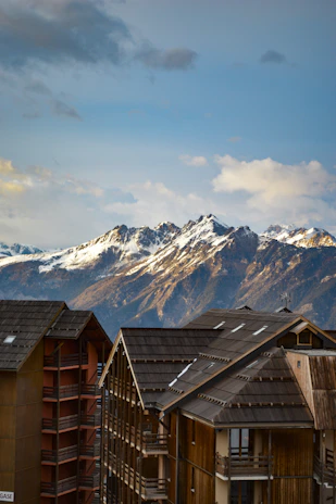 Majestic view of the snowy Swiss Alps with a cozy chalet nestled among pine trees.