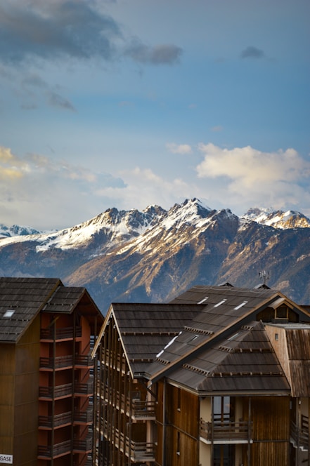 A cozy ski chalet with snow-covered mountains in the background and a welcoming concierge at the door