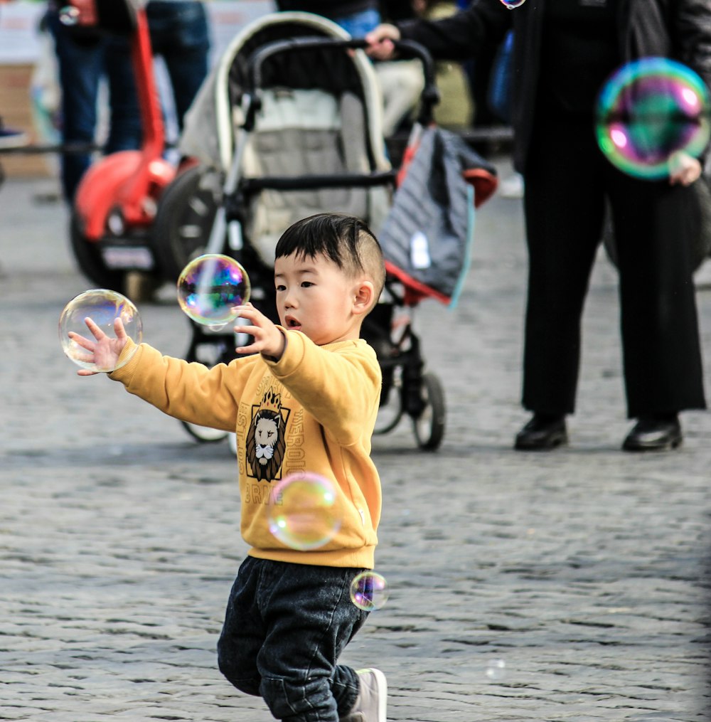 boy in yellow sweater playing with bubbles