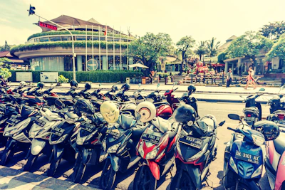 A group of colorful scooters lined up along a tropical road with lush greenery.