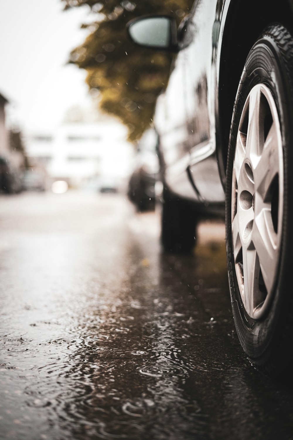 black car passing on road during rainy day