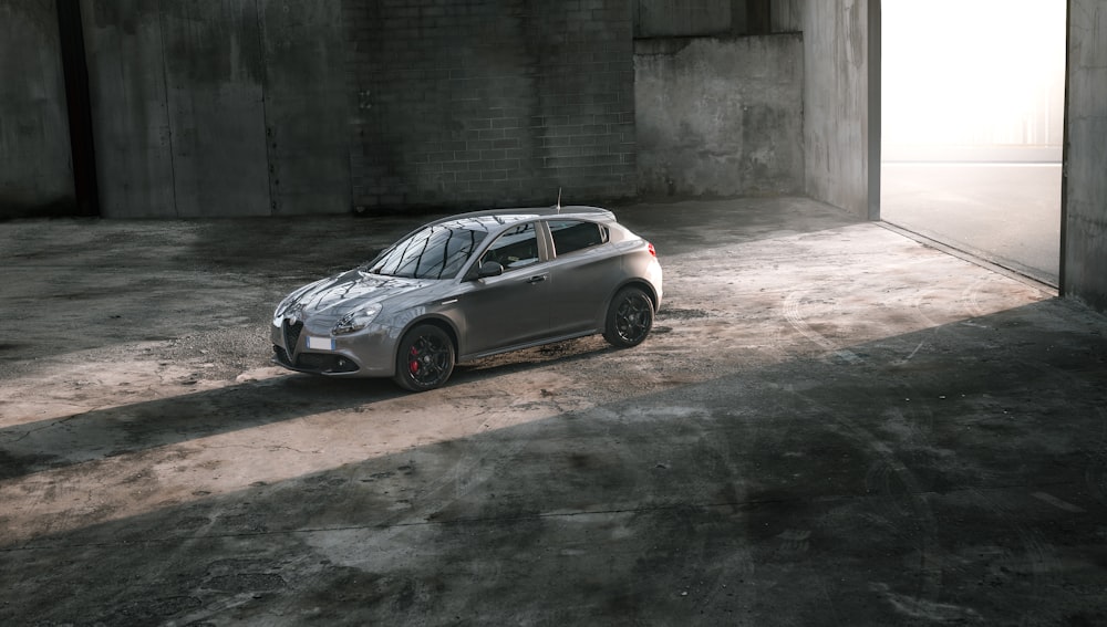 Alfa Romeo 3 porte berlina grigia all'interno di garage vuoto