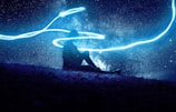 A person meditating under a canopy of stars.
