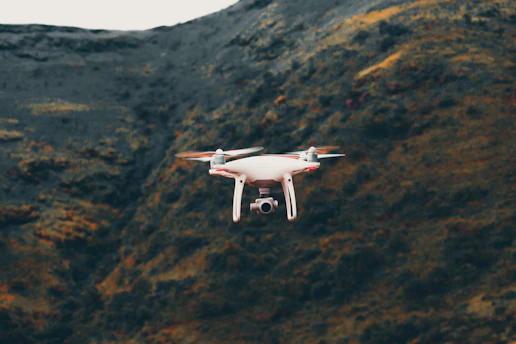A sleek drone hovering over a scenic mountain landscape during golden hour.