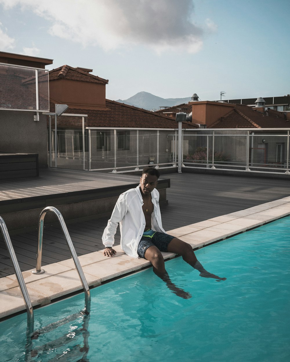 man in white button-up long-sleeved shirt sitting at side of pool