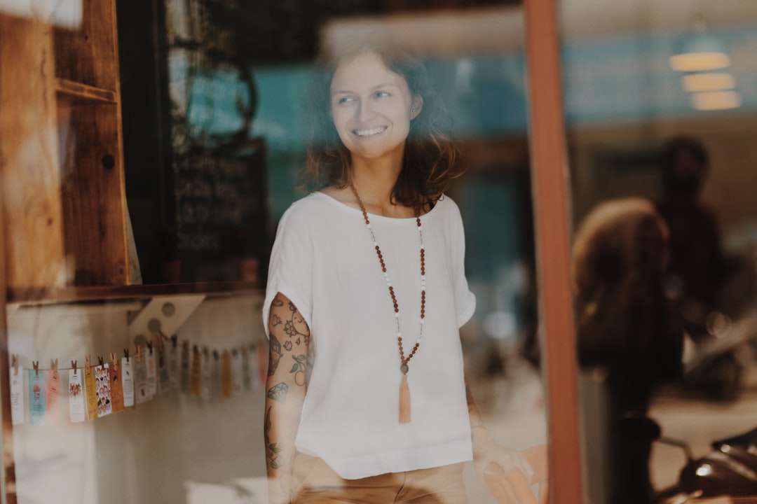 woman in white top standing by the window and smiling