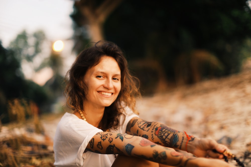 Mulher sorridente na camiseta branca sentada na praia