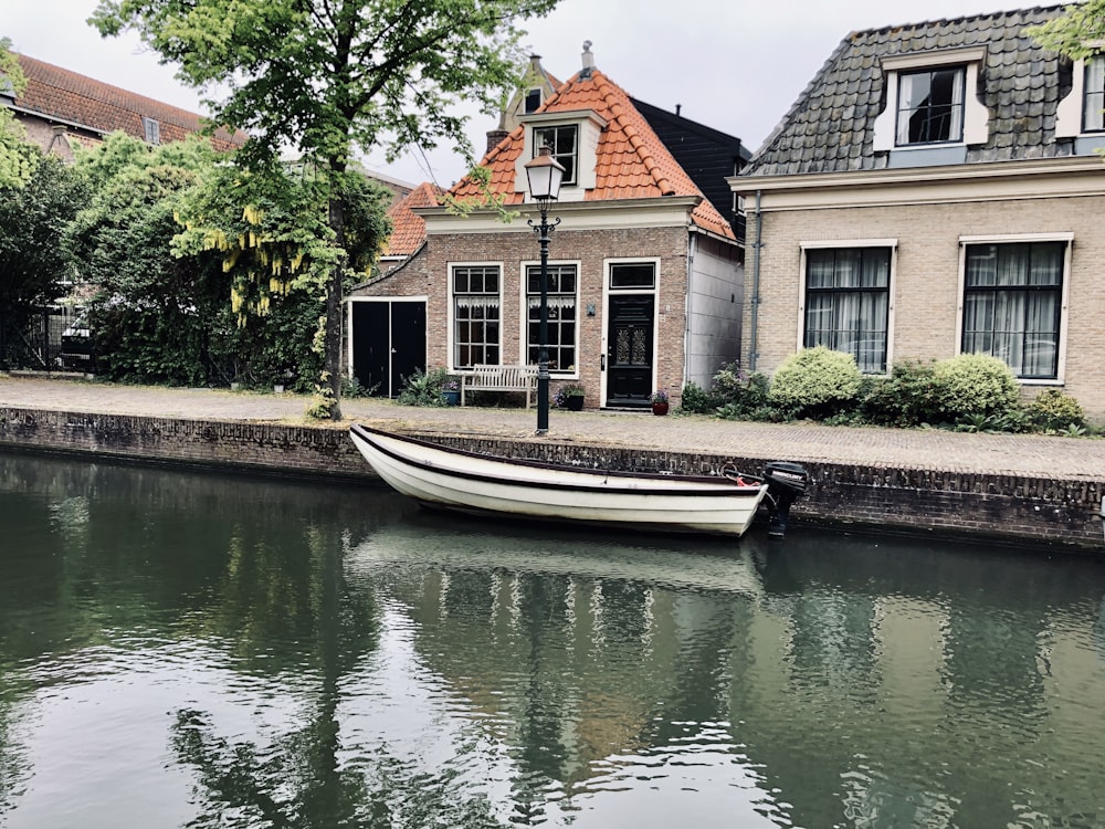 white motorboat moored in riverside in front of houses