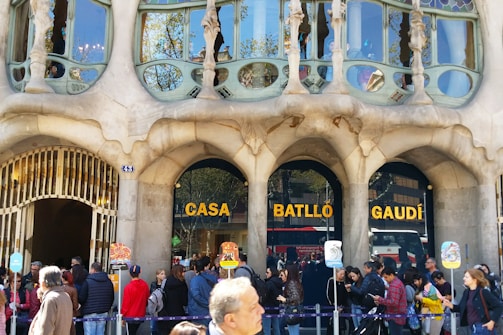 An ornate building facade featuring organic, flowing design elements characteristic of modernist architecture. People are gathered outside, indicating it is a popular tourist spot.