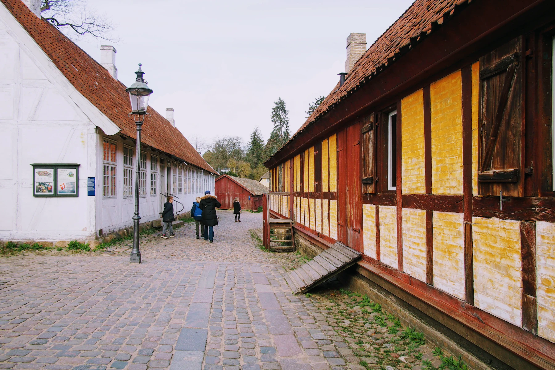 Half-timbered historic buildings line a cobbled street at Den Gamle By in Aarhus.