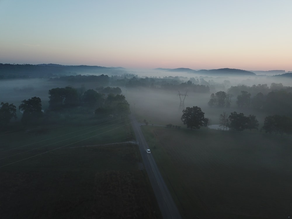 nebliger Morgen auf dem Land mit einsamem weißem Auto auf der Autobahn