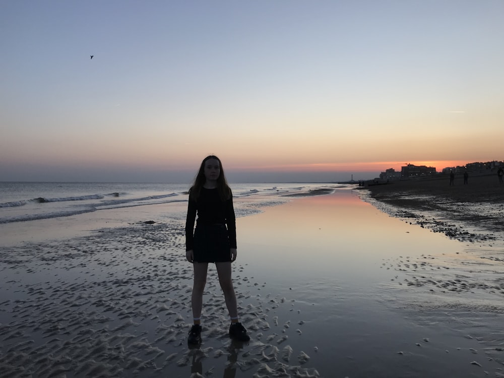 woman standing on seashore during blue hour