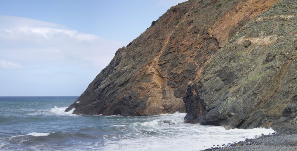 white waves breaking on brown rock hill in beach