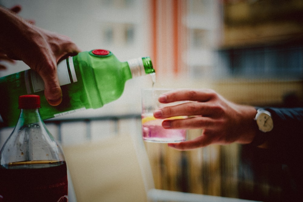 person pouring liquid to drinking glass