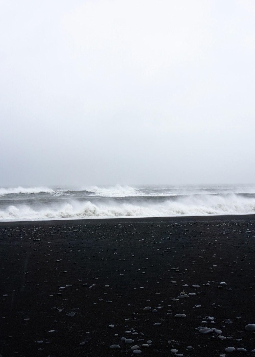 black sand and ocean waves under fogs