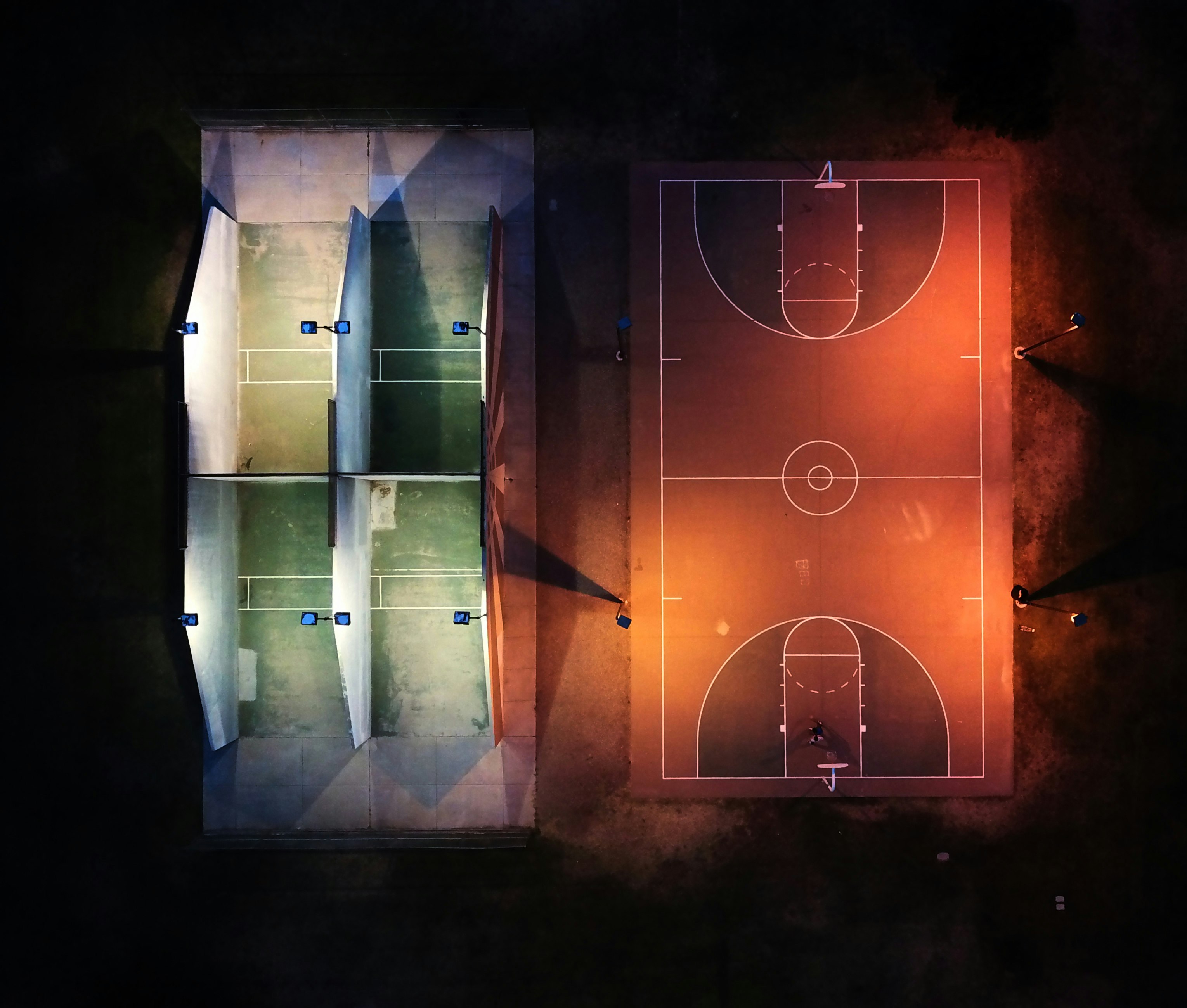 Aerial view of racquetball court as well as a basketball court at night.