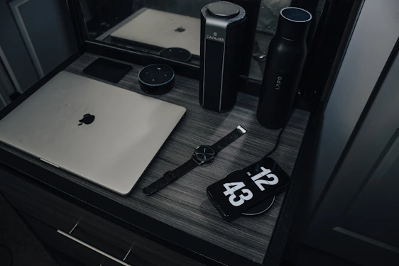 A vibrant workspace with sleek electronics and a person using a smartwatch, embodying modern innovation.